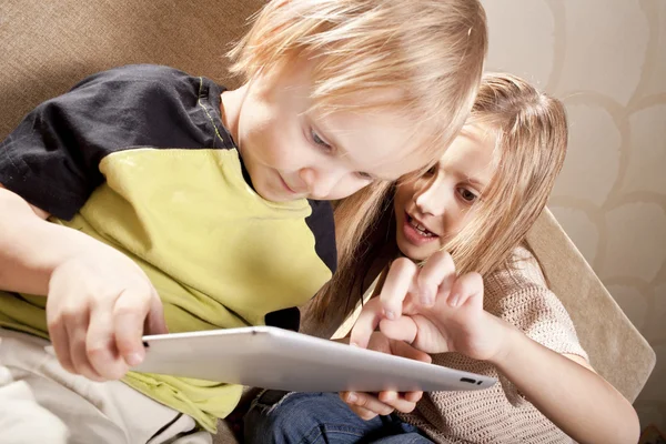 Улыбающаяся девочка и мальчик с планшетным компьютером — стоковое фото