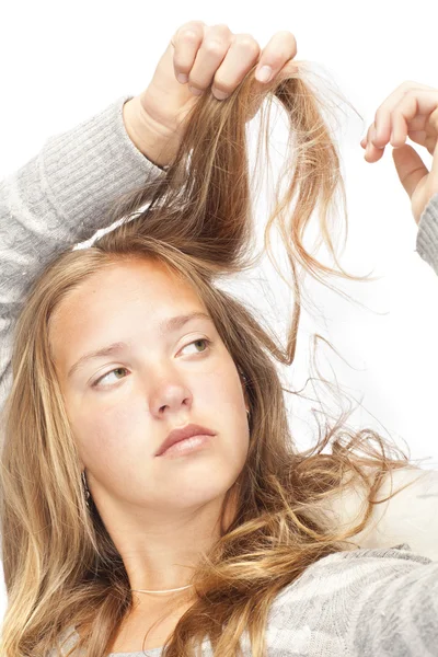 Ung blond tjej tittar på håret — Stockfoto
