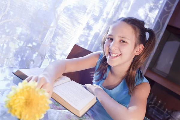 Positiva scolara con libro a casa — Foto Stock