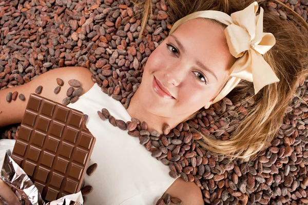 Beautiful girl with chocolate on cocoa beans — Stock Photo, Image