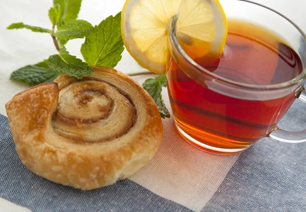 Cup of tea with cinnamon Danish bun — Stock Photo, Image