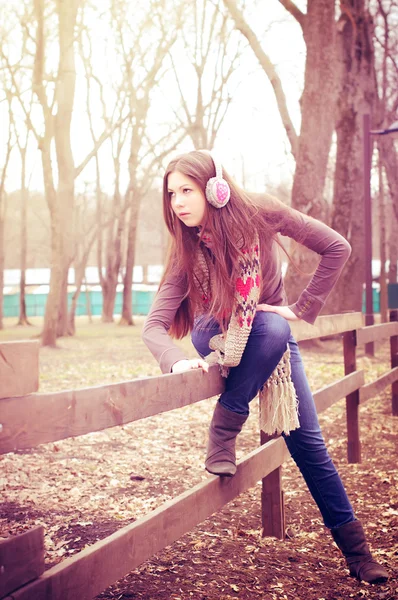 De jonge vrouw zit op een hek — Stockfoto