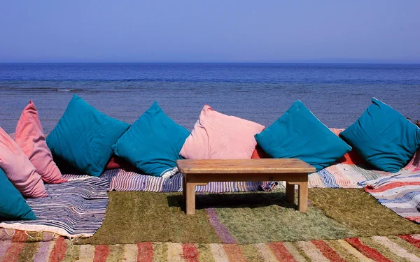 Blanket and table on beach — Stock Photo, Image