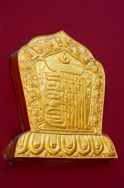 Золотое украшение на красной стене ламазария — стоковое фото