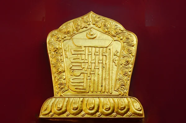 Decoração dourada na parede vermelha de um lamasery — Fotografia de Stock