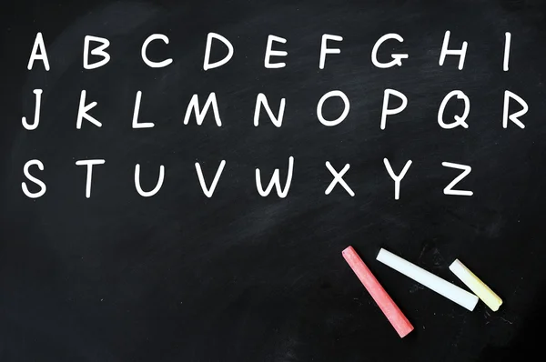 Alfabeto inglés escrito a mano con tiza blanca en una pizarra — Foto de Stock