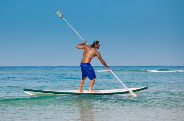 O tipo com um remo numa prancha de surf . — Fotografia de Stock