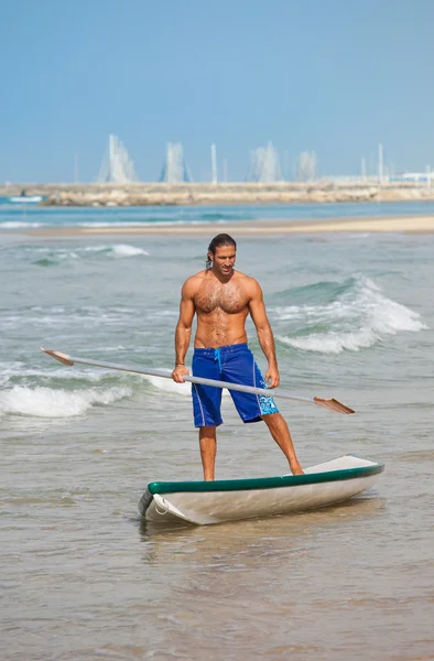 El tipo con un remo en una tabla de surf . — Foto de Stock