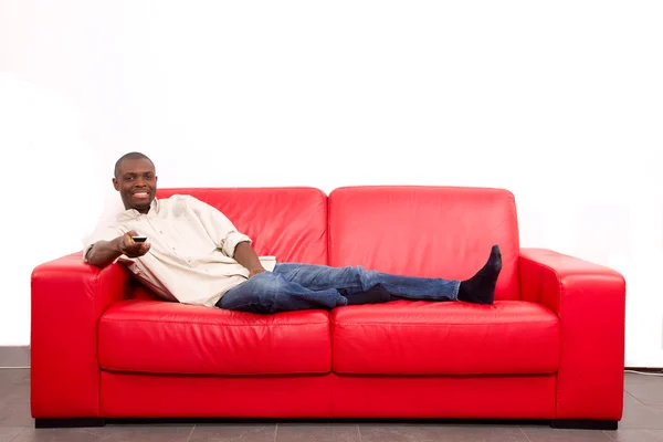 Человек на диване с дистанционным управлением — стоковое фото