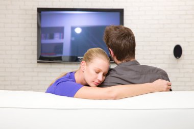 Man watching tv woman embraces him clipart