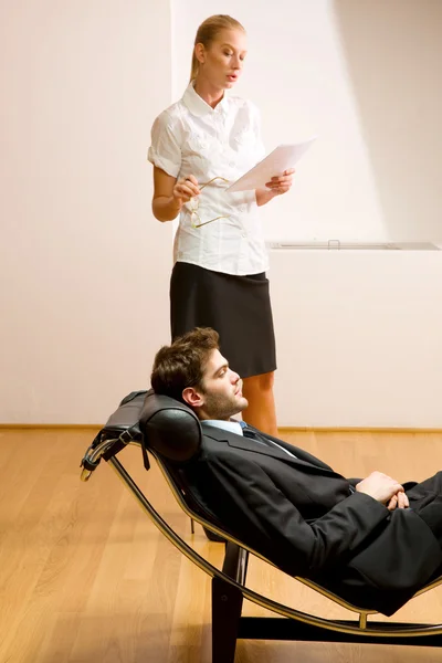 Vrouw leest man liggend op chaise longue — Stockfoto