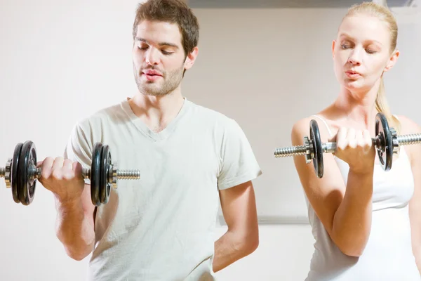 Man and woman lifting dumbbell in gym — Stockfoto