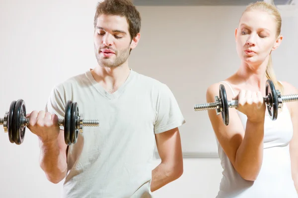 stock image Man and woman lifting dumbbell in gym