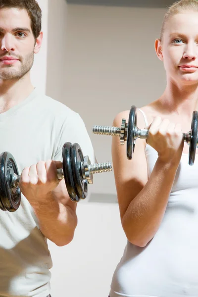 Man and woman lifting dumbbell in gym — Stock Photo, Image