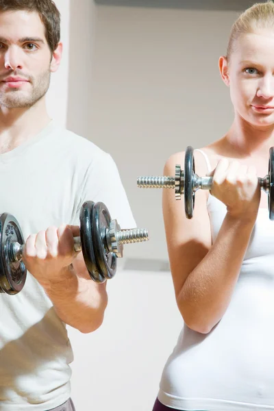 Man and woman lifting dumbbell in gym — Stockfoto