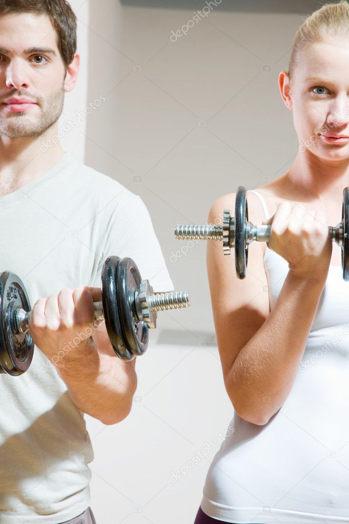 Man and woman lifting dumbbell in gym
