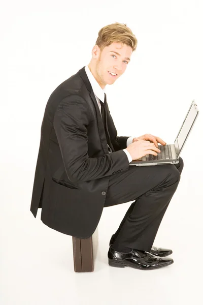Uomo d'affari con computer portatile seduto su una valigia — Foto Stock