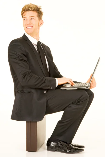 Бізнесмен з ноутбуком сидить на валізі — стокове фото