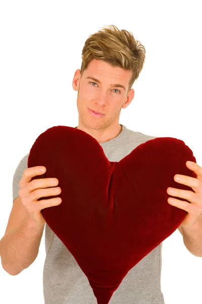 Young man with a heart shaped pillow — Stock Photo, Image