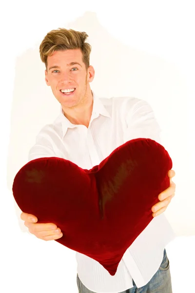 Young man handing a heart shaped pillow — Stock Photo, Image