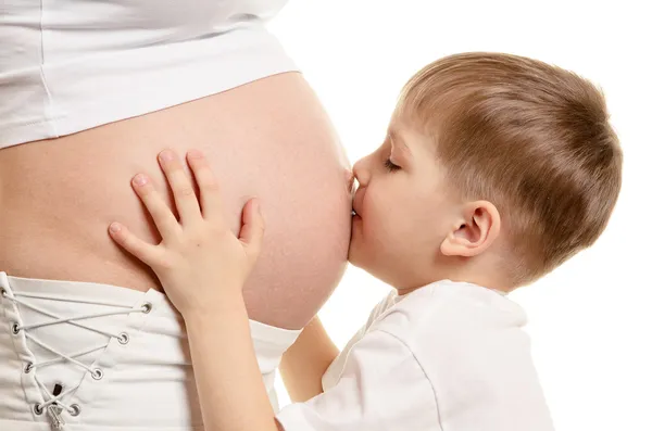 Мальчик целует беременную женщину. — стоковое фото