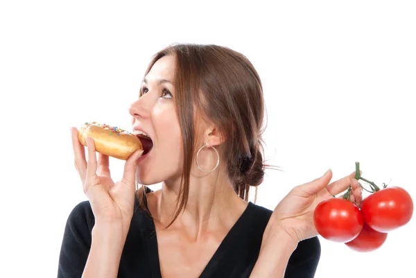 Kvinna jämföra ohälsosamma donut och organiska röda tomater — Stockfoto