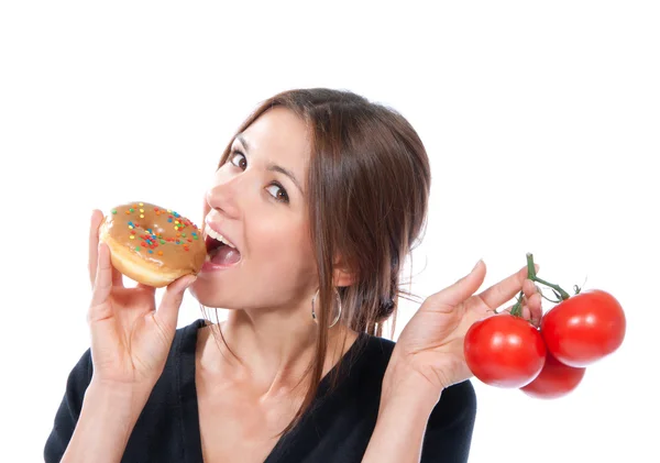 Kvinna jämföra ohälsosamma donut och organiska röda tomater — Stockfoto