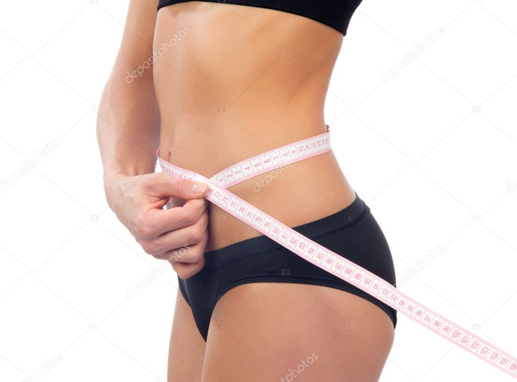 Slender woman measuring her waist with metric tape measure after a