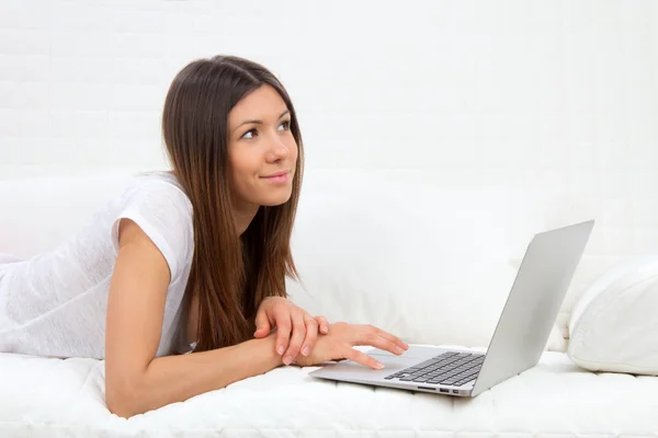 Kobieta, leżąc na kanapie z laptopem płacąc rachunki online — Zdjęcie stockowe