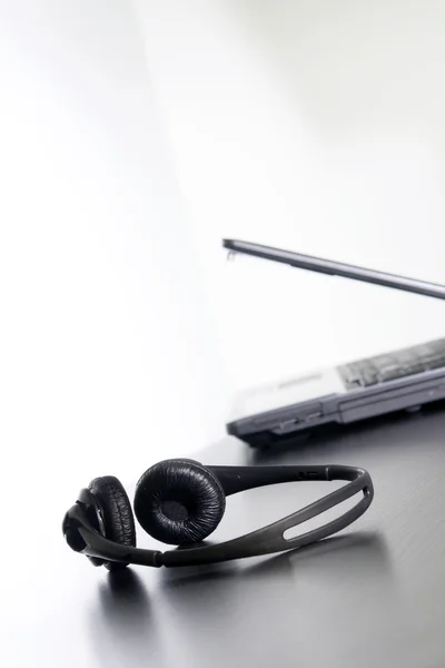 Computer and headset on the table, nothing else. — Stock Photo, Image