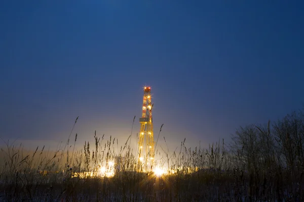 Oil rig in the mist, illuminated at night. — Stock Photo, Image
