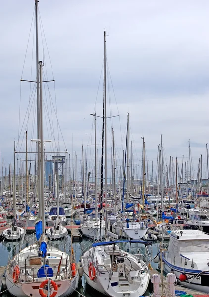 Båtar och segel båtar i barcelona hamn. — Stockfoto