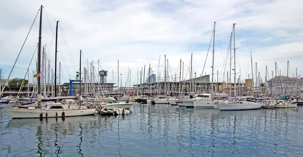 Båtar och segel båtar i barcelona hamn. — Stockfoto