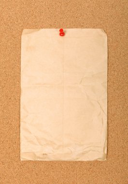 Wrinkled brown envelope attached to cork board with red pin. Emp clipart