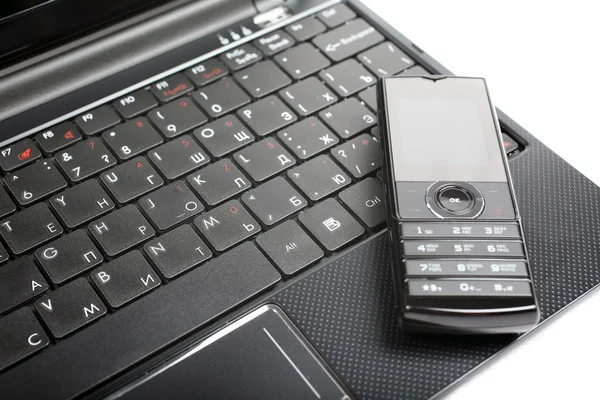 Mobilní telefon na notebook izolovaných na bílém pozadí. — Stock fotografie
