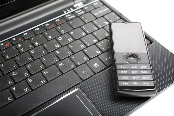 stock image Mobile phone laying on notebook isolated on white background.