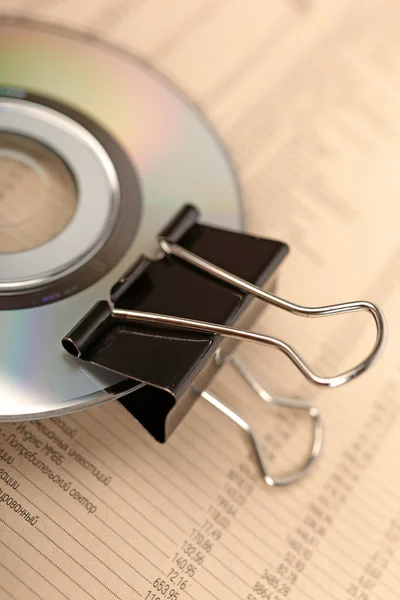 Close photo of paperclip attached to disk laying on financial ne — Stock Photo, Image
