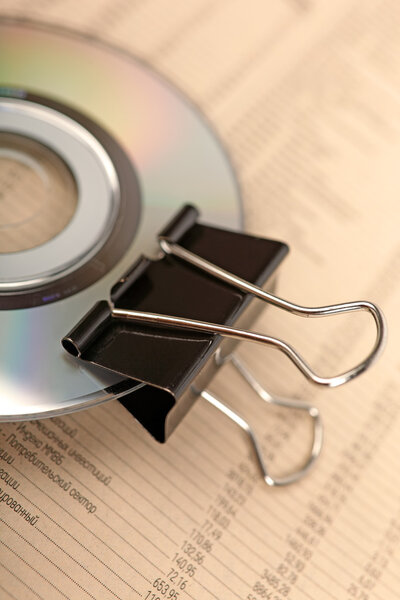 Close photo of paperclip attached to disk laying on financial ne