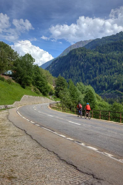Cyklisté na silnici mezi švýcarských Alp, Evropa. — Stock fotografie