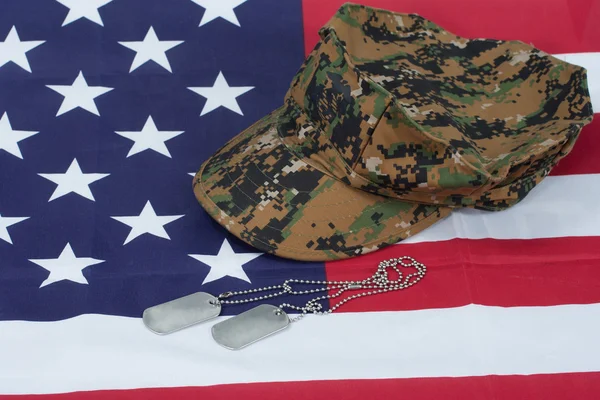 Us marine camouflage cap with blank dog tag on us flag background