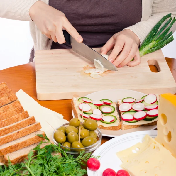 Chopping spring onion and preparing sandwiches — Stock Photo, Image