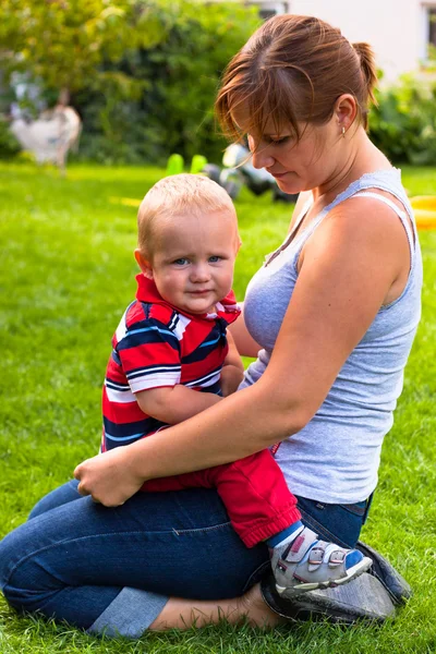 Kobieta i maluch siedząc na trawie — Zdjęcie stockowe