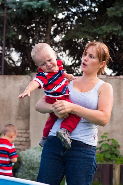 Mulher segurando grumpy chorando criança menino ao ar livre — Fotografia de Stock