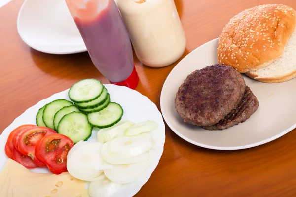 Table with hamburgers and vegetable — Stock Photo, Image
