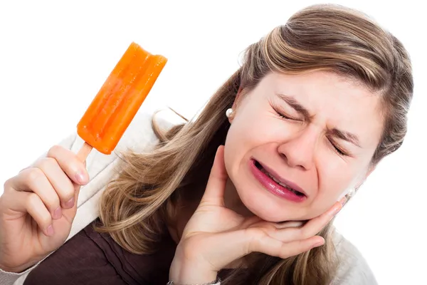얼음 사탕을 먹는 과민 치아를 가진 여자 로열티 프리 스톡 사진