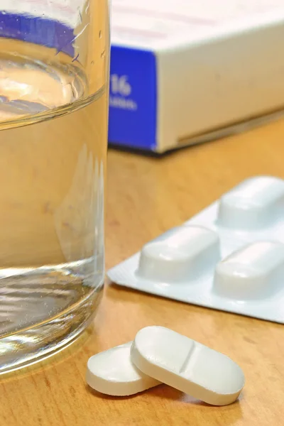 Таблетки и вода на столе — стоковое фото