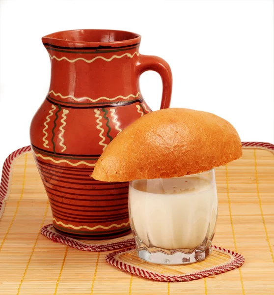 A jarra de cerâmica, um copo de leite, um pão . — Fotografia de Stock