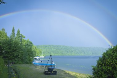 Double rainbow on a lake with beach and campfire clipart