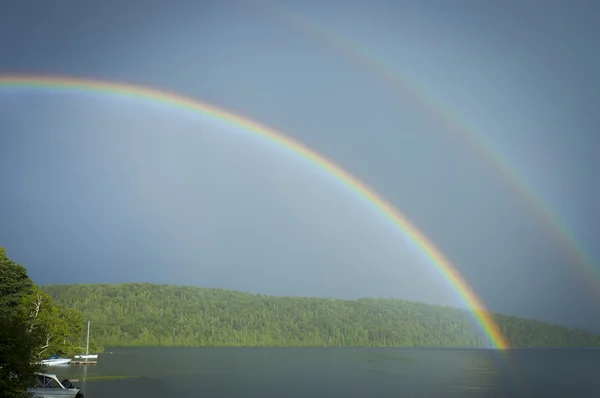 Doppio arcobaleno su un lago con barche — Foto Stock