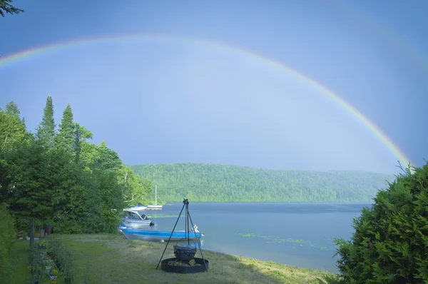 Doble arco iris en un lago con playa y fogata — Foto de Stock